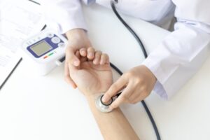 Checking pulse using stethoscope over wrist.